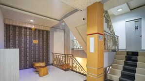 Eine Hotelhalle mit Treppe, einer Holzsäule und einer Wand mit Muster.