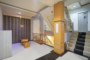 Una hall d'albergo con una scala, una colonna di legno e un muro decorato.