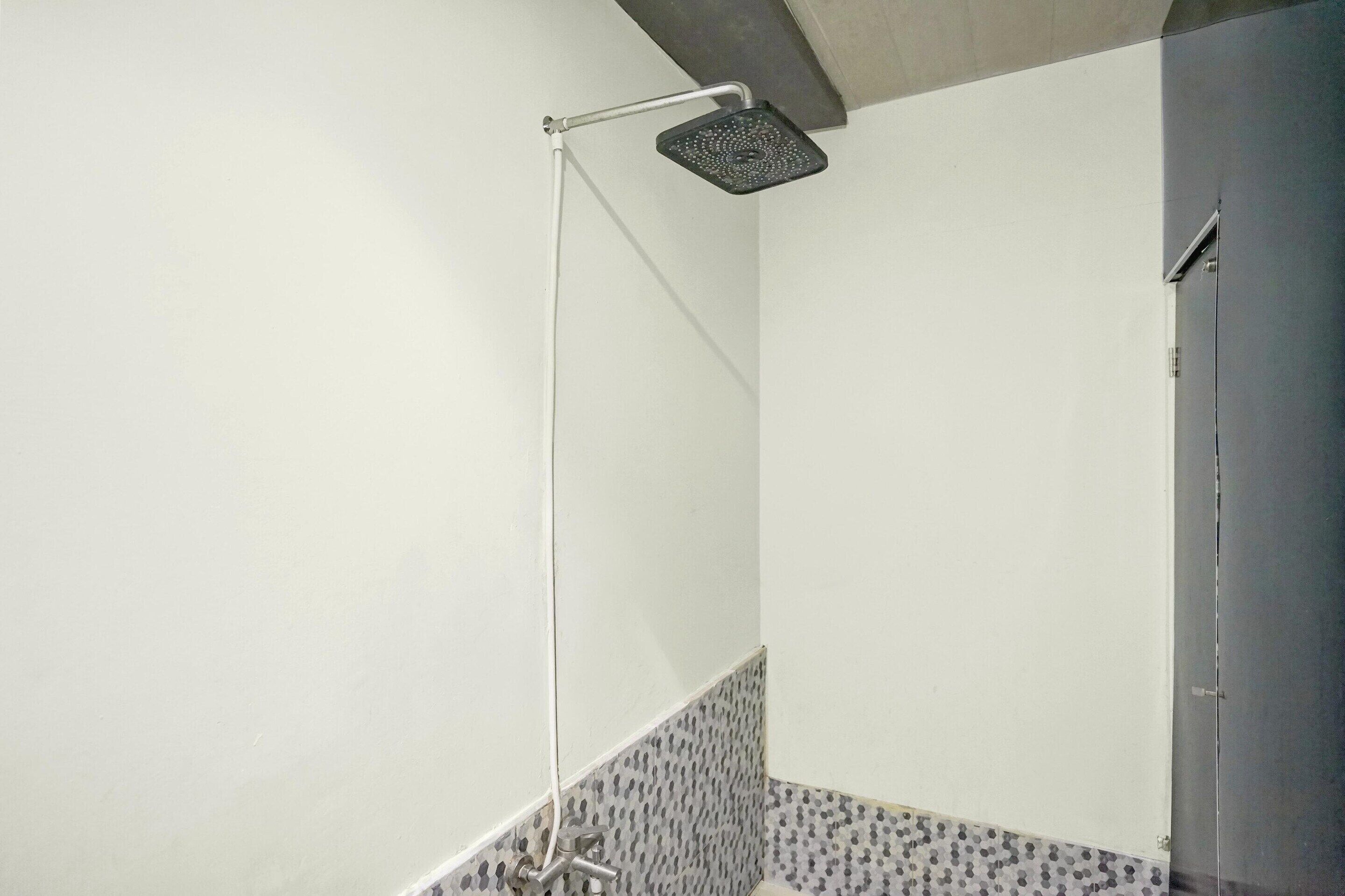 Een hoek van een badkamer met een douche, een betegelde muur en een deur.