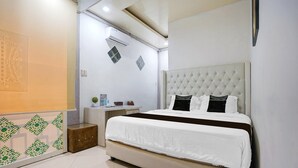 Ein Schlafzimmer mit einem großen Bett, einem Nachttisch, einer Wand-Klimaanlage und einer dekorativen Wandverkleidung.