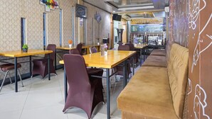 Ein Restaurantinneres mit Tischen, Stühlen, einer Couch und einer Kaffeebar.