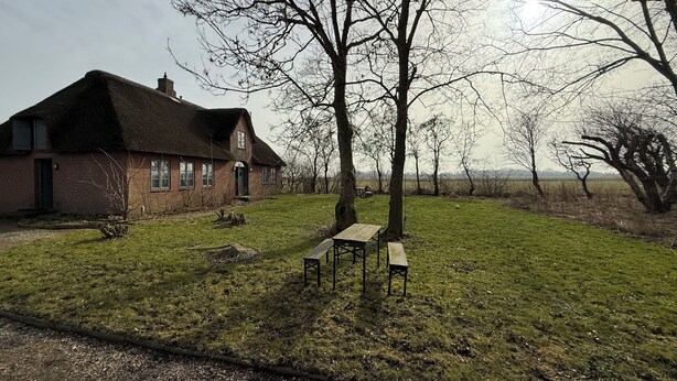 A brick house with a thatched roof, a grassy yard, and a picnic table. - Dream thatched house in a secluded location directly off Sylt. (Emmelsbüll-Horsbüll)