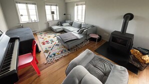 A living room with a piano, a sofa, a rug, and a fireplace. - Dream thatched house in a secluded location directly off Sylt. (Emmelsbüll-Horsbüll)