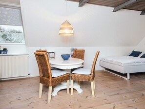 A room with a round table, two wicker chairs, a white sofa, and a hanging light fixture. - 5 Star Holiday Home in Ansager (Ansager)