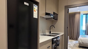 Een kleine keuken met een zwarte koelkast, een inbouwoven en een vaatwasser.