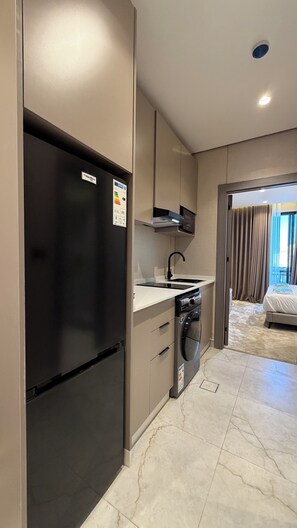 A compact kitchen with a black refrigerator, a built-in oven, and a dishwasher. - 303 Tara-jre Jabal Al Lweibdeh With Stunning View (Amman)