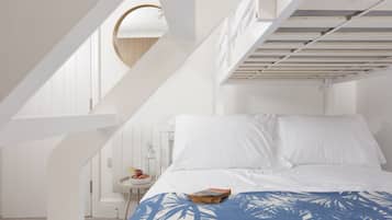 A bedroom with a bunk bed, a round mirror, a small table with fruit, and a patterned bedspread.