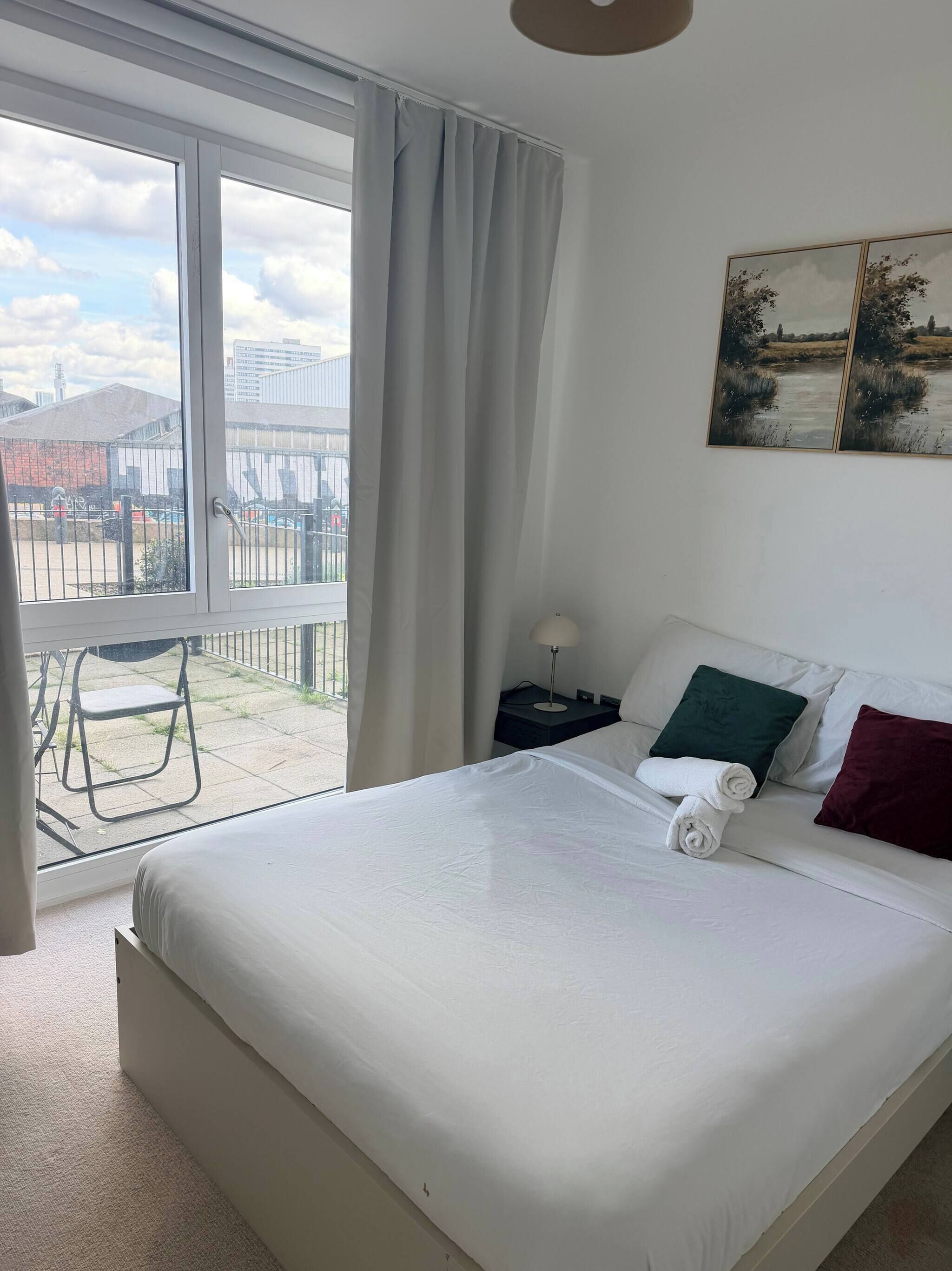 Et hotelværelse med en stor seng, byudsigt, en balkon og et billede på væggen.