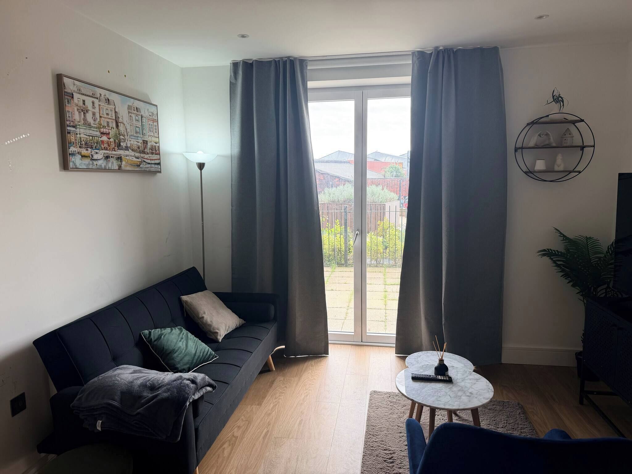 Ein modernes Wohnzimmer mit einer Couch, einem kleinen runden Tisch und Blick durch eine Glastür.