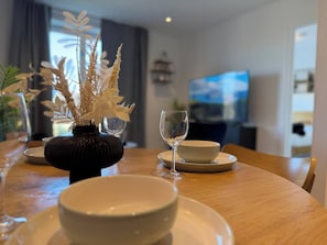 A dining table with a vase of dried plants, a wine glass, and bowls. - One Bedroom West Midlands Retreat (Birmingham)