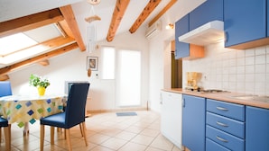 Une cuisine avec des meubles de couleur bleue, un plafond en bois et un coin repas comprenant une table et des chaises.