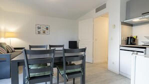 A modern kitchen with white appliances, a dining area with a table and chairs, and a door leading to another room. - Scenic Riviera Home Near sea (Grasse)