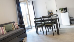 A modern living room with a sofa, chairs, a dining table, and a refrigerator. - Scenic Riviera Home Near sea (Grasse)