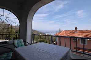 Ein Balkon mit Tisch und Stühlen, mit Blick auf ein Wohngebiet und das Meer.