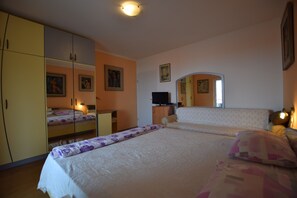 A bedroom with two beds, a wardrobe, a television, and a mirror. - Comfortable Apartment With Terrace and sea View.outdoor Kitchen for Use! (Opatija)