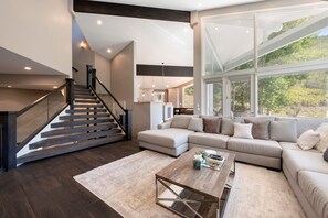 A modern living room with a staircase, a sectional sofa, and a coffee table. - Spacious 5BR, 5BA Deer Valley Nordic Village Haus—ideal mountain retreat for 12. (Park City)