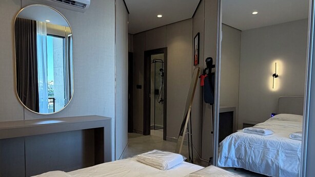 A hotel room with a bed, a large mirror, an air conditioning unit, and a door leading to a bathroom. - 304 Tara-jre Al Lweibdeh 2bdr With Stunning View (Amman)