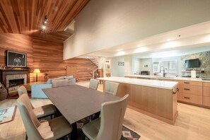 A modern kitchen with a central island, wooden ceiling, and a dining area with a table and chairs. - Spacious 4BR retreat in Deer Valley with stunning mountain views. (Park City)