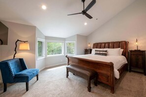 A bedroom with a large bed, a ceiling fan, a desk lamp, and a chair. - Spacious 4BR retreat in Deer Valley with stunning mountain views. (Park City)
