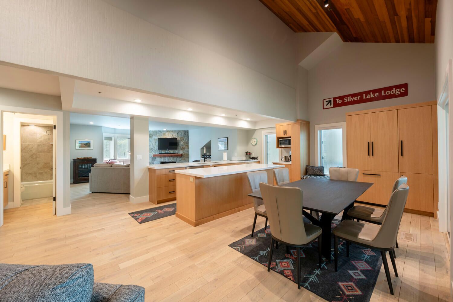 Una cocina moderna con una isla central, armarios de madera y un comedor con mesa y sillas.