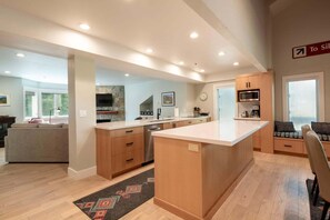 A modern kitchen with wooden cabinets, a central island, and a dining area with a bench. - Spacious 4BR retreat in Deer Valley with stunning mountain views. (Park City)