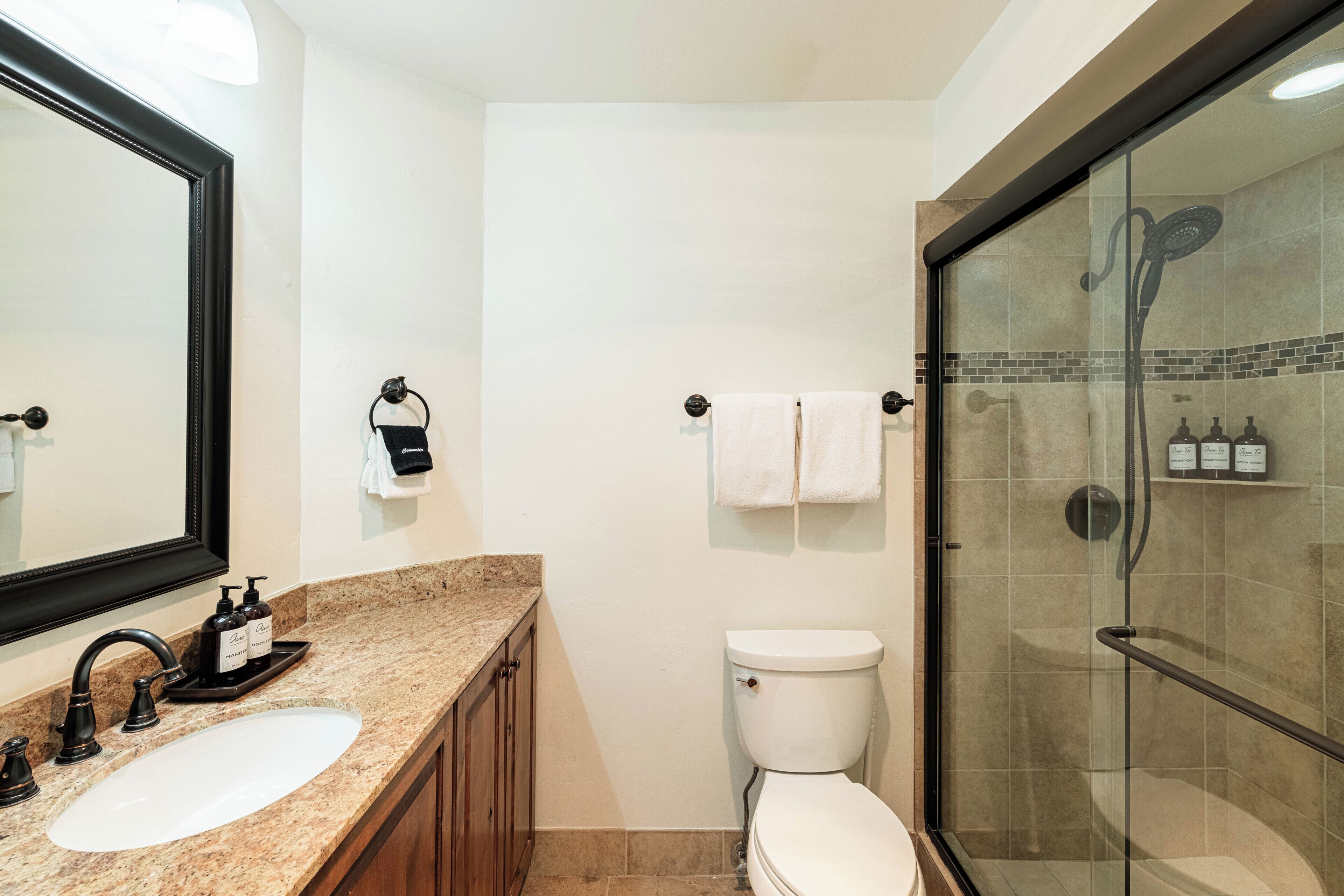 A bathroom with a sink, toilet, and glass-enclosed shower.