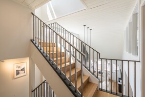 A staircase with metal railings and wooden steps, leading to a room with a white ceiling and a framed picture on the wall. - Modern Park City Retreat | Private Hot Tub Near Slopes (Park City)