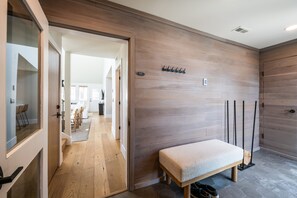 A modern interior with a wooden bench, a coat rack, and a door leading to a dining area. - Modern Park City Retreat | Private Hot Tub Near Slopes (Park City)