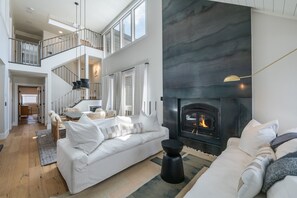 A spacious living area with a fireplace, a staircase, and a balcony. - Modern Park City Retreat | Private Hot Tub Near Slopes (Park City)