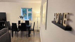 Un soggiorno moderno con zona pranzo, un divano grigio, televisore e finestra con vista.