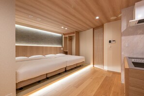Een moderne hotelkamer met een houten plafond, een inbouwbed, een klein keukentje en een schuifdeurkast.