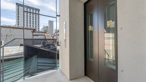 A hotel entrance with a glass door, a metal staircase, and a view of a cityscape. - 【新築OPEN】浅草寺徒歩1分! 雷門20秒/檜風呂・Simmons/最大収容人数8名/渋谷新宿浅草 (Tokyo)