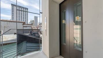 A hotel entrance with a glass door, a metal staircase, and a view of a cityscape.