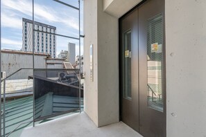 Ein Hotel mit Eingang, einer Glastür, einer Metalltreppe und Blick auf eine Stadtansicht.