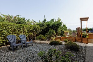 A garden with two Adirondack chairs, a wooden pergola, and various plants. - Enjoy a bright and comfortable 2‑bedroom suite with a private entrance, full kitchen, and one bathroom. The space accommodates up to six guests and includes a cozy living area, smart TV, Wi‑Fi (Nanaimo)