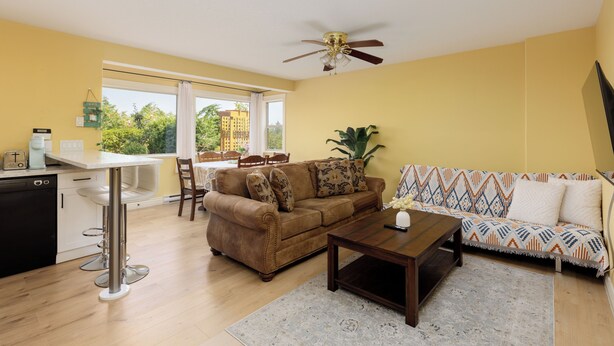 A living room with a sofa, coffee table, and a dining area with chairs and a table.