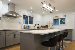 Uma cozinha moderna com uma ilha grande, banquetas e um exaustor de aço inoxidável.