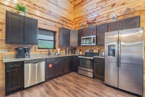 Eine moderne Küche mit Holzwänden, Edelstahlgeräten und einer Arbeitsplatte aus Granit.