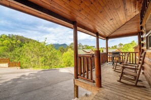 Eine Holzterrasse mit Blick auf einen Wald und Berge.
