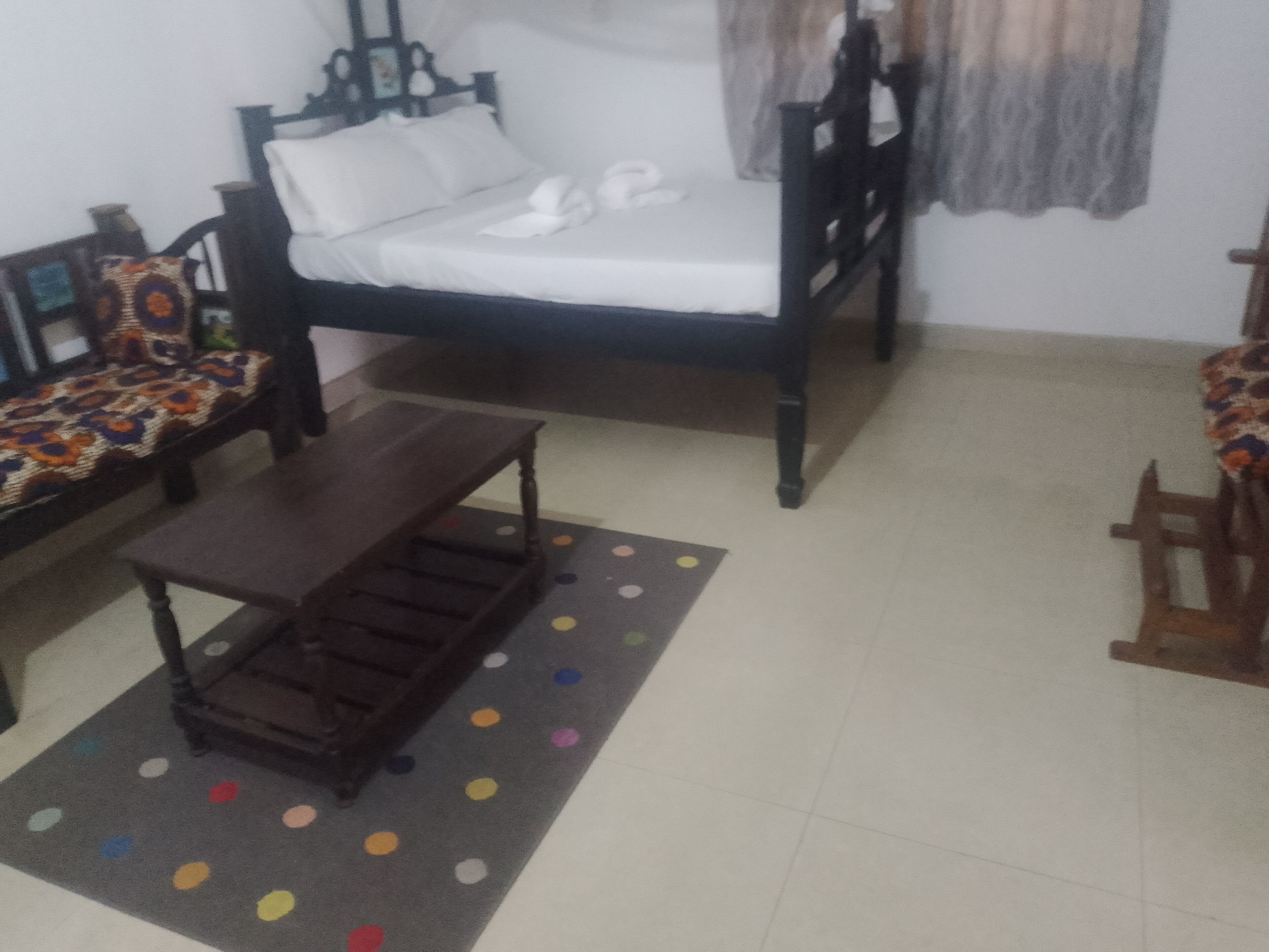 Ein Zimmer mit einem Bett, einem Schlafsofa, einem Holztisch und einem Teppich mit Punkten.