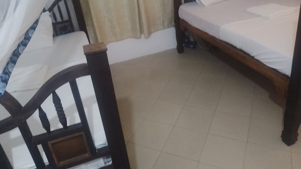 A bedroom with a wooden bed, a nightstand, and a window with curtains. - Kahawa sun set view kiwengwa  (Kiwengwa)