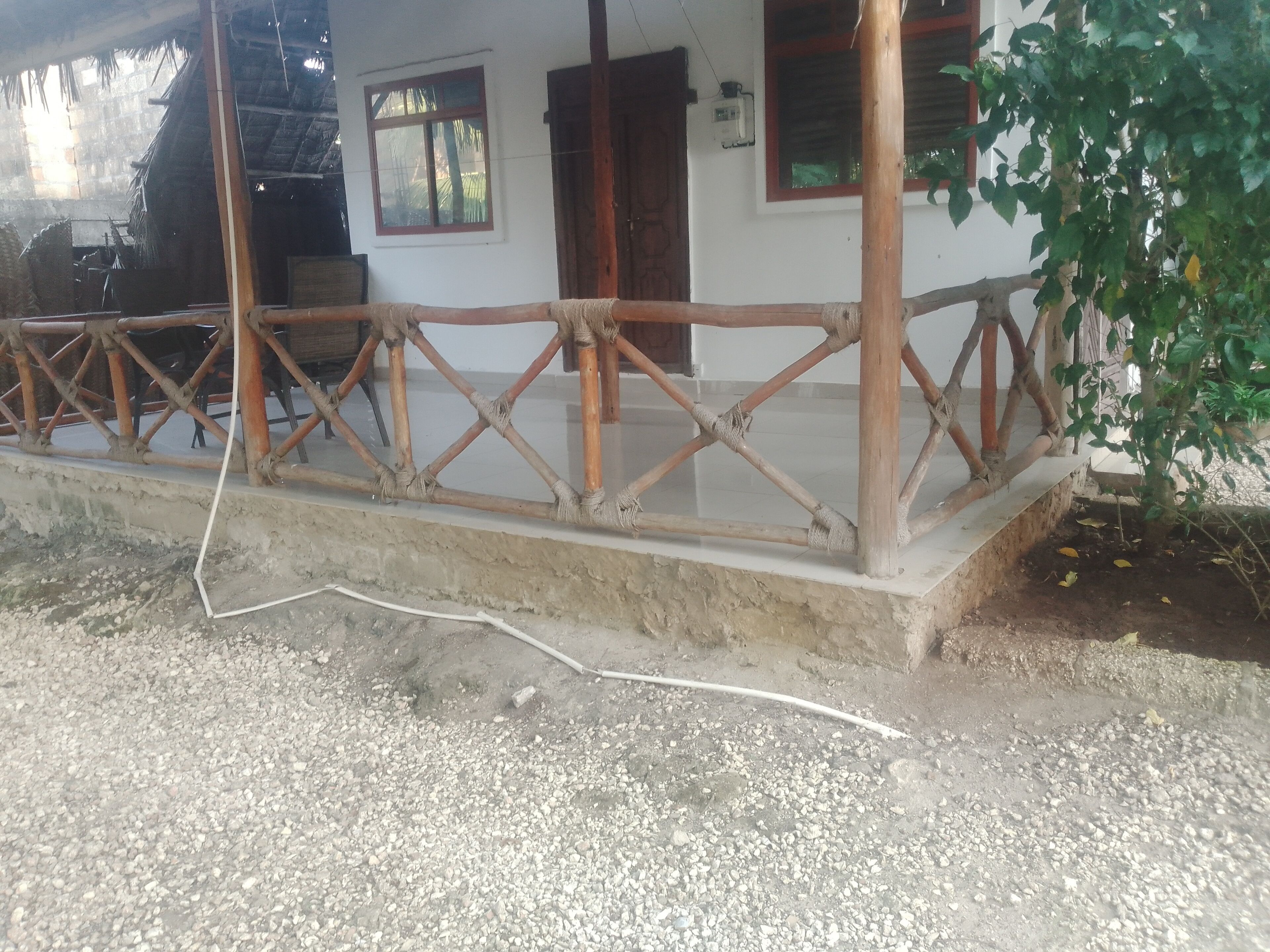 Un edificio con fachada blanca, cerca de madera y base de concreto.