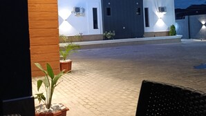 A modern building with a paved entrance, a covered seating area, and potted plants.