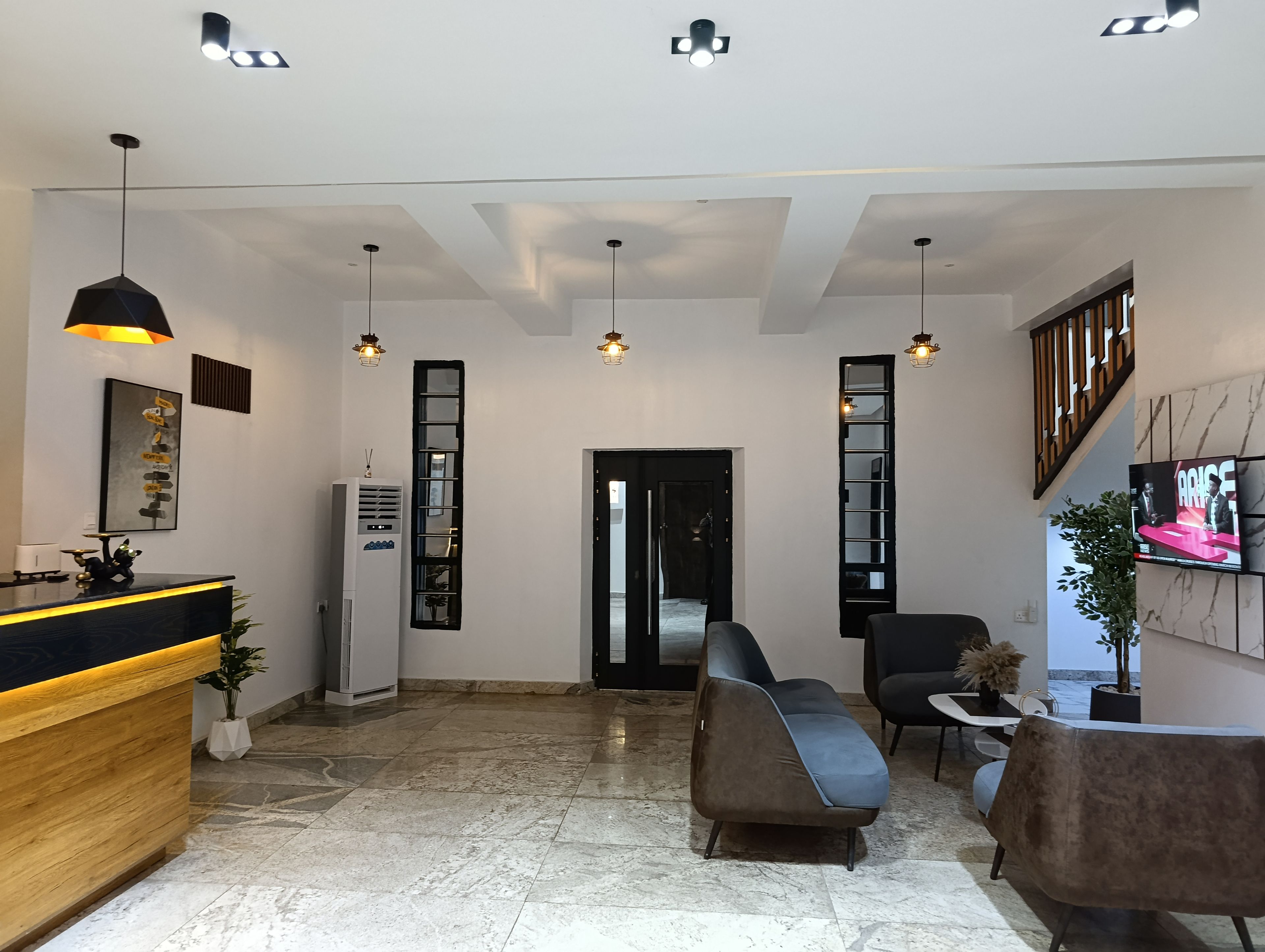 A modern reception area with a wooden counter, a large mirror, and a seating area with a sofa and chairs.