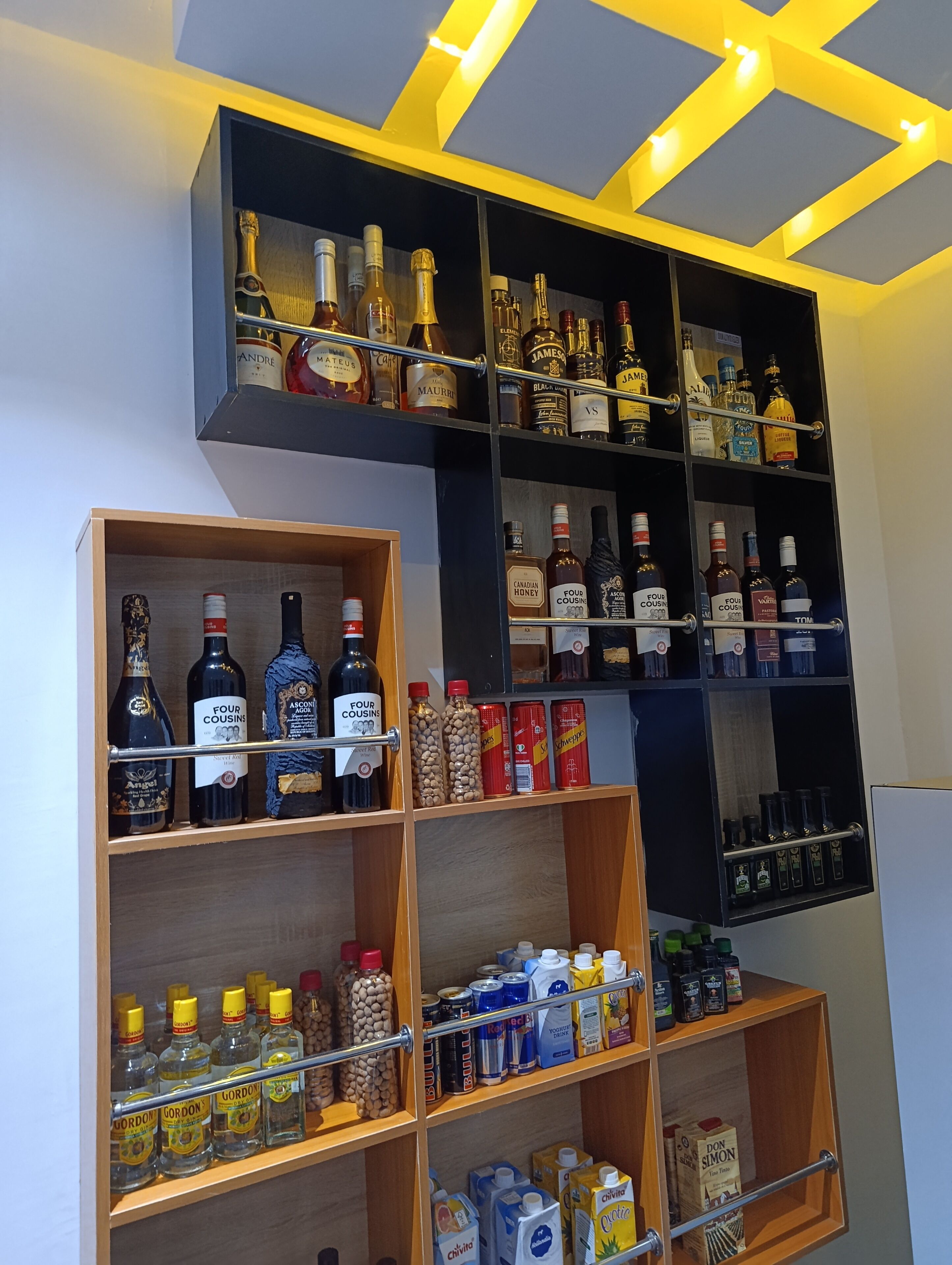 A liquor cabinet with various bottles and cans, including brands like Four Cousins and Gordon's.