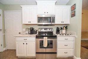 A kitchen with white cabinetry, a stainless steel oven, a microwave, and a coffee maker. - Private Spa, 2 seater golf cart, Life Style ID's (Lady Lake)