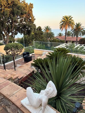 A courtyard with a statue, a palm tree, and a view of the sea. - Wonderful villa with a view of the sea (Saint-Raphaël)