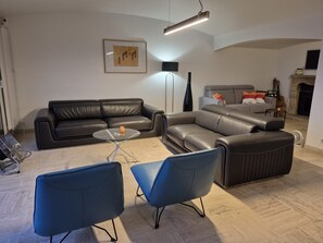Ein modernes Wohnzimmer mit einer Couch, zwei Sesseln, einem Couchtisch und einem Kamin.