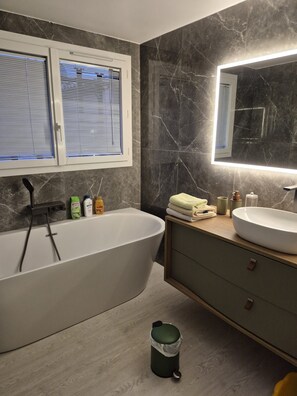 Ein modernes Badezimmer mit einer freistehenden Badewanne, einem Waschtisch und einem großen Spiegel.