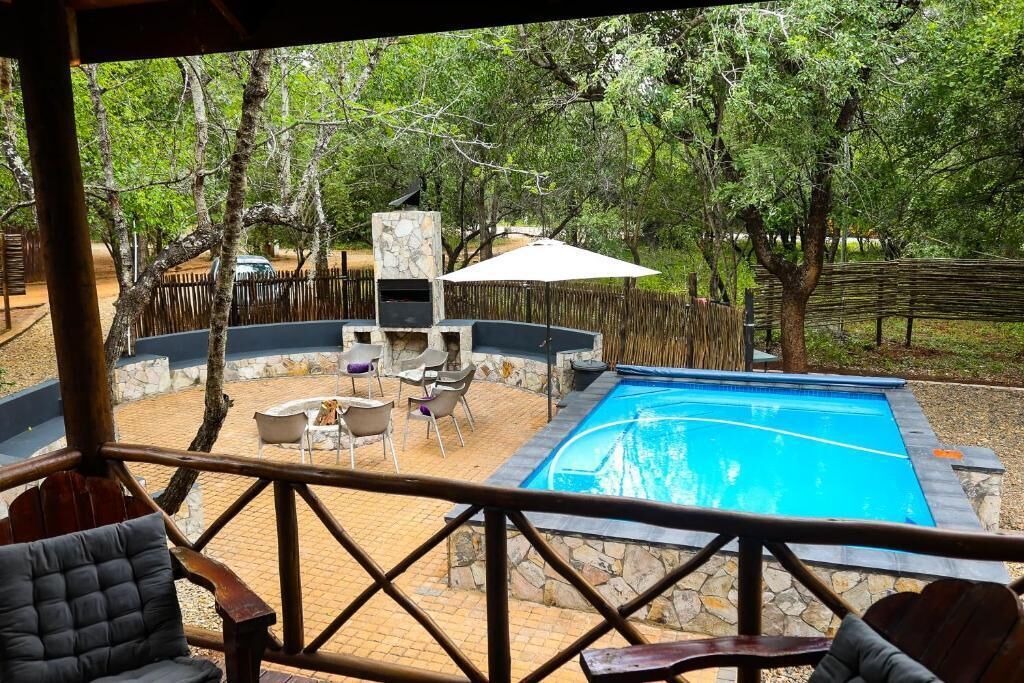 Zona de piscina con muros de piedra, una barbacoa y mobiliario para exteriores.